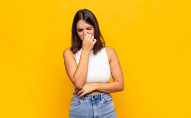 Genç ve güzel bir kadın iğrenç ve nahoş bir kokuyu koklamamak için burnunu tutuyor.