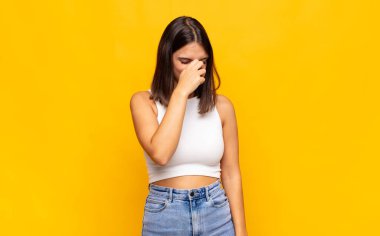 Genç ve güzel bir kadın stresli, mutsuz ve hayal kırıklığına uğramış, alnına dokunuyor ve şiddetli baş ağrısı çekiyor.