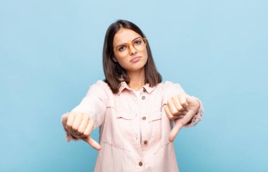 Genç, güzel bir kadın üzgün, hayal kırıklığına uğramış ya da kızgın görünüyor. Anlaşmazlıkta baş parmaklarını gösteriyor. Hayal kırıklığına uğramış hissediyor.