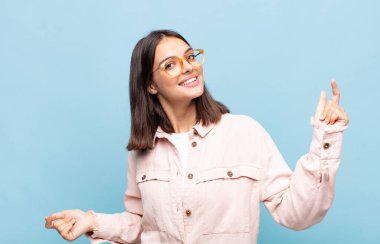 Genç, güzel bir kadın gülümsüyor, kaygısız hissediyor, rahat ve mutlu, dans ediyor ve müzik dinliyor, bir partide eğleniyor.