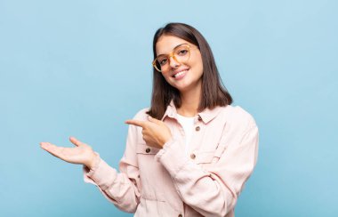 Genç, güzel bir kadın gülümsüyor, mutlu, kaygısız ve tatmin olmuş hissediyor, fotokopi alanındaki konsepte veya fikre işaret ediyor.