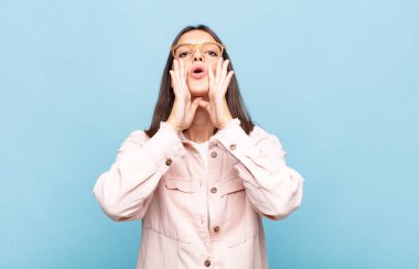 Genç, güzel bir kadın mutlu, heyecanlı ve pozitif hissediyor. Elleri ağızda, bağırıyor.