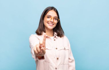 Genç ve güzel bir kadın gururla gülümsüyor ve gururla bir numaralı pozu veriyor, kendini lider gibi hissediyor.