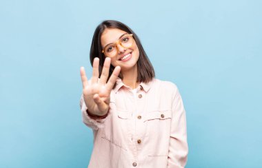 Genç, güzel bir kadın gülümsüyor ve arkadaş canlısı görünüyor. Dört ya da dört numarayı gösteriyor. Elleri önde, geri sayıyor.