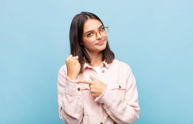 Genç ve güzel bir kadın sabırsız ve kızgın görünüyor, saati gösteriyor, dakiklik istiyor, zamanında gelmek istiyor.