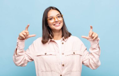 Genç, güzel bir kadın iki eliyle kendi gülüşünü çiziyor, olumlu ve mutlu görünüyor, sağIık kavramı.