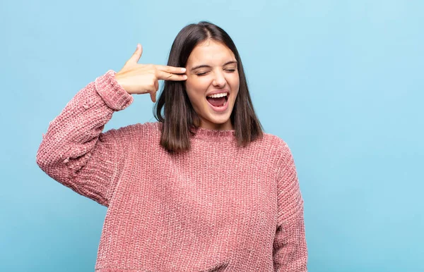 Genç ve güzel bir kadın mutsuz ve stresli görünüyor. İntihar jesti. Elinde silah işareti yapıyor.