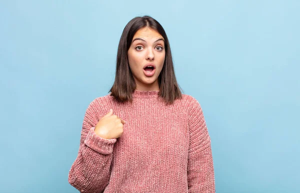 Genç ve güzel bir kadın şok olmuş ve şaşırmış görünüyor, ağzı açık, kendini işaret ediyor.