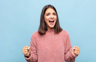 Genç ve güzel bir kadın öfkeli bir ifadeyle ya da yumruklarıyla başarıyı kutlarken agresif bir şekilde bağırıyor.