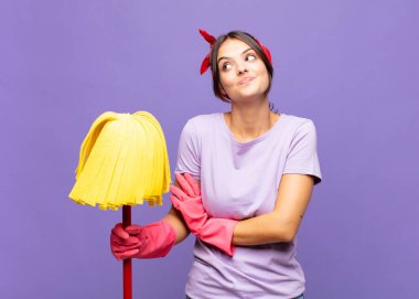 Genç, güzel bir kadın omuz silkiyor, kafası karışık ve kararsız, kolları bağlı ve şaşkın görünüyor.