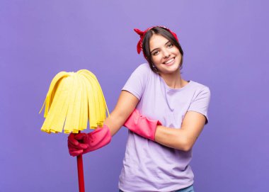 Genç ve güzel bir kadın kollarını kavuşturup mutlu bir şekilde gülüyor, rahat, pozitif ve tatmin edici bir pozla.