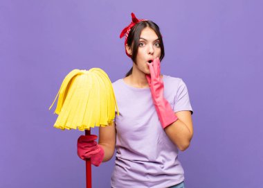 Genç ve güzel bir kadın şok olmuş ve korkmuş hissediyor, ağzı açık ve elleri yanaklarında korkmuş görünüyor.