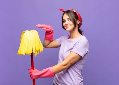 Genç ve güzel bir kadın bir objeyi iki eliyle fotokopi alanında tutuyor, bir objeyi gösteriyor, sunuyor ya da reklamını yapıyor.