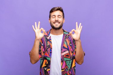 Genç adam odaklanmış ve meditasyon yapıyor, kendini tatmin olmuş ve rahatlamış hissediyor, düşünüyor ya da bir seçim yapıyor.