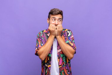 Genç adam endişeli, gergin, stresli ve korkmuş görünüyor. Tırnaklarını yiyor ve yanal fotokopi alanı arıyor.