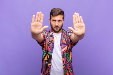 Genç adam ciddi görünüyor, mutsuz, kızgın ve hoşnutsuz giriş yasaklandı ya da her iki avuçta da dur diyor.