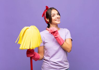 Genç ve güzel bir kadın neşeyle gülümsüyor ve yan taraftaki fotokopi alanını işaret ediyor, mutlu ve tatmin olmuş hissediyor.