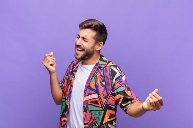 Genç adam gülümsüyor, tasasız hissediyor, rahat ve mutlu, dans ediyor ve müzik dinliyor, bir partide eğleniyor.