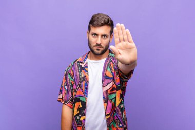 Genç adam ciddi, sert, hoşnutsuz ve kızgın görünüyor. Avuç içinin açık olması jesti durduruyor.