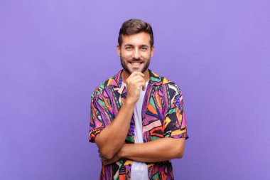 Genç adam mutlu görünüyor ve gülümsüyor. El pençe divan, merak ediyor ya da soru soruyor. Seçenekleri karşılaştırıyor.