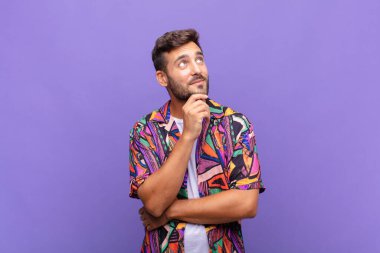 Genç adam mutlu bir şekilde gülümsüyor ve hayal kuruyor ya da şüphe ediyor.