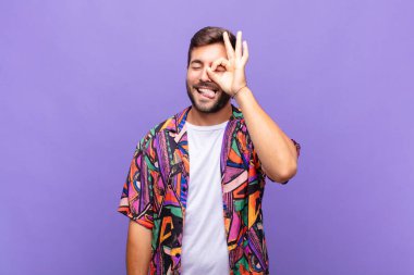 Genç adam mutlu bir şekilde gülümsüyor, şaka yapıyor ve gözetleme deliğinden bakıyor, sırları gözetliyor.