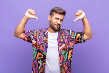 Genç adam üzgün, hayal kırıklığına uğramış ya da kızgın görünüyor. Anlaşmazlıkta baş parmaklarını gösteriyor. Hayal kırıklığına uğramış hissediyor.