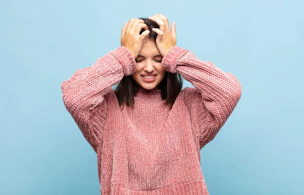 Genç ve güzel bir kadın stresli ve endişeli, depresif ve hayal kırıklığına uğramış hissediyor, iki elini de başa kaldırıyor.