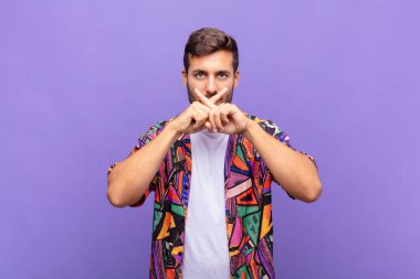 Genç adam ciddi ve hoşnutsuz görünüyor. İki parmağının önde olması reddedilerek sessizlik istiyor.