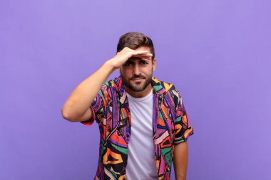 Genç adam şaşkınlık ve şaşkınlık içinde bakıyor, uzaktan bakıyor, izliyor ya da arıyor.