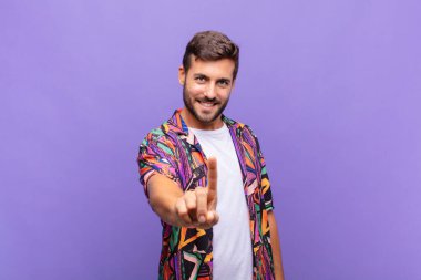 Genç adam gururla gülümsüyor ve gururla bir numaralı pozunu veriyor, kendini lider gibi hissediyor.