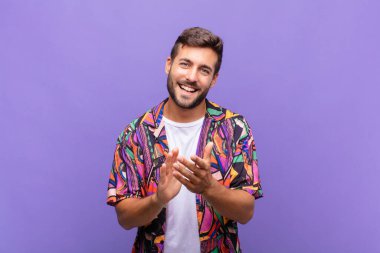 Genç adam mutlu ve başarılı hissediyor, gülümsüyor ve alkışlıyor, alkışlarla tebrik ediyor.