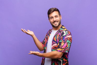 Genç adam gururla ve güvenle gülümsüyor, mutlu ve tatmin olmuş hissediyor ve fotokopi alanında bir konsept gösteriyor.