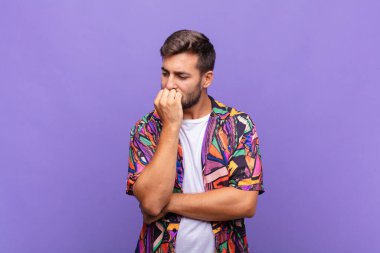 Genç adam ciddi, düşünceli ve endişeli, elleri çenesine bastırılmış, yan bakıyor