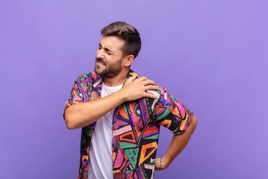 Genç adam yorgun, stresli, endişeli, hayal kırıklığına uğramış ve depresyonda, sırtı ya da boynu ağrıyan