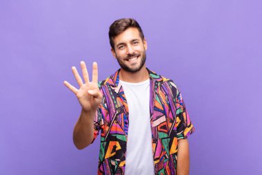Genç adam gülümsüyor ve arkadaş canlısı görünüyor, dört ya da dört numarayı gösteriyor, eli önde, geriye doğru sayıyor.