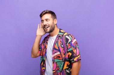 Genç adam gülümsüyor, tuhaf bir şekilde yan tarafa bakıyor, dedikoduları dinlemeye ya da bir sırrı duymaya çalışıyor.