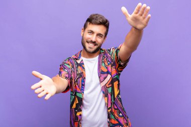 Genç adam neşeyle gülümsüyor sıcak, dostça, sevgi dolu bir kucak veriyor, mutlu ve sevimli hissediyor.