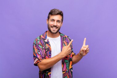 Genç adam mutlu bir şekilde gülümsüyor ve her iki elinle de fotokopi uzayında nesne gösteriyor.