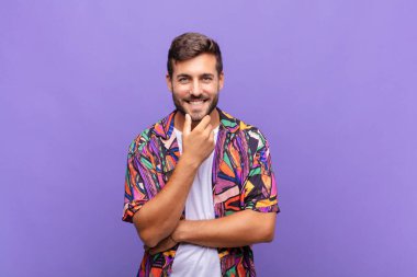 Genç adam gülümsüyor, hayattan zevk alıyor, mutlu, arkadaş canlısı, tatmin olmuş ve tasasız.