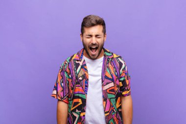 Genç adam agresif bir şekilde bağırıyor, çok kızgın, hayal kırıklığına uğramış, öfkeli ya da sinirli görünüyor.