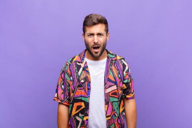 Genç adam şok olmuş, kızgın, sinirli ya da hayal kırıklığına uğramış, ağzı açık ve öfkeli görünüyor.
