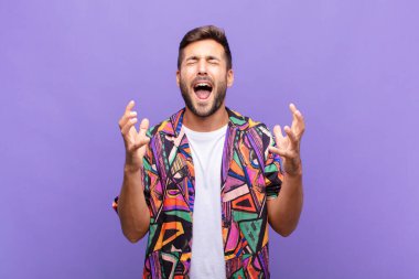 Genç adam öfkeyle bağırıyor, stresli hissediyor ve ellerini havaya kaldırıp neden ben diye bağırıyor.