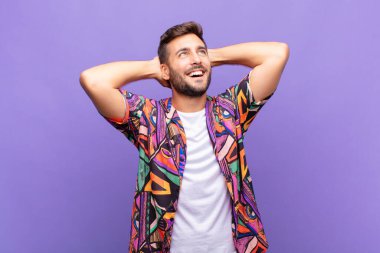 Genç adam gülümsüyor ve rahatlıyor, tatmin oluyor, kaygısız, neşeli ve rahatlatıcı.