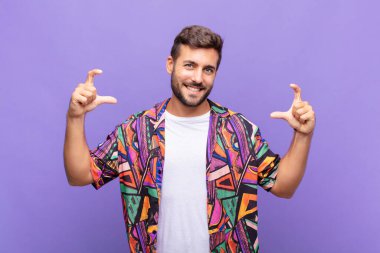 Genç adam kendi gülüşünü iki eliyle çiziyor, olumlu ve mutlu görünüyor, sağIık kavramı