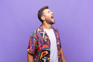 Genç adam öfkeyle bağırıyor, agresif bir şekilde bağırıyor, stresli ve sinirli görünüyor.