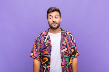 Genç adam merak ediyor, mutlu düşünceler ve fikirler düşünüyor, hayal kuruyor, kenarda yer arıyor.