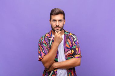 Genç adam ciddi görünüyor, kafası karışık, kararsız ve düşünceli, seçenekler ve seçimler arasında şüpheci.