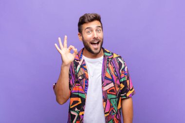 Genç adam kendini başarılı ve tatmin olmuş hissediyor, ağzı açık gülümsüyor, elle imza atıyor.