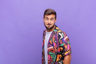 Genç adam şapşal, çılgın, şaşırmış bir ifadeyle, yanakları şişmiş, doldurulmuş, şişman ve yemekle dolu